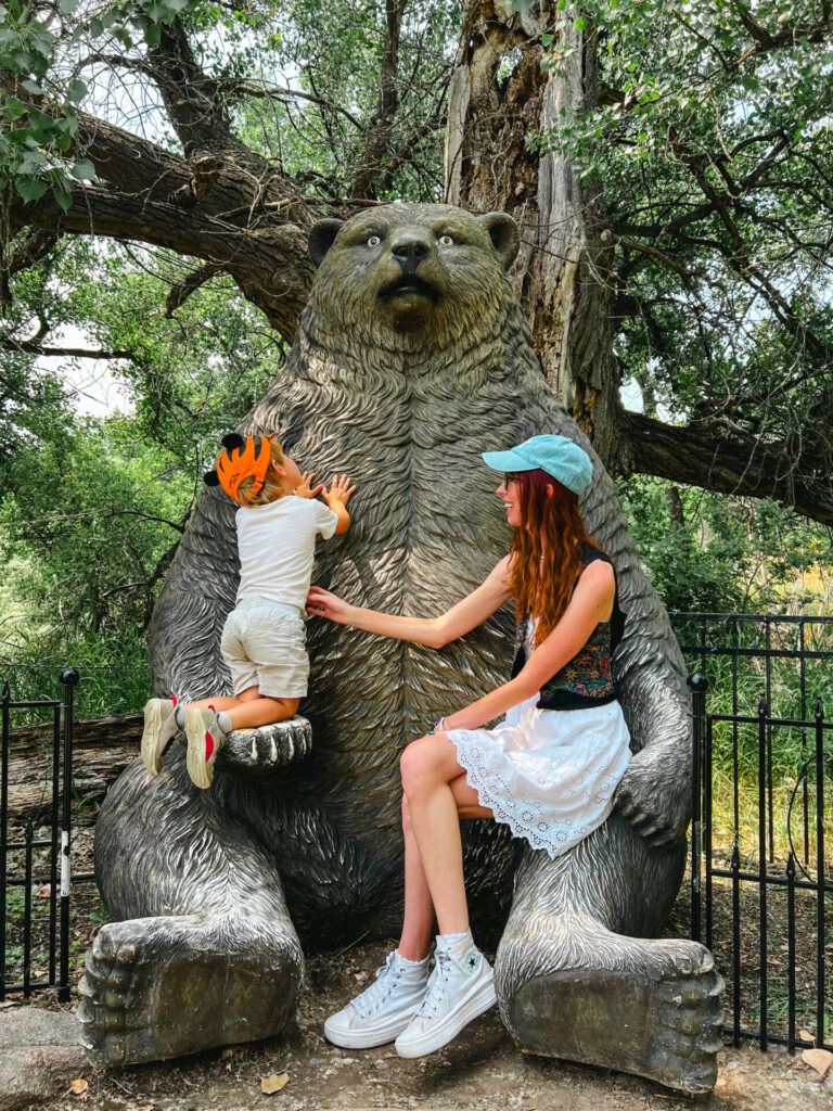 Mom and kid sitting on bear statue at ZooMontana in Billings