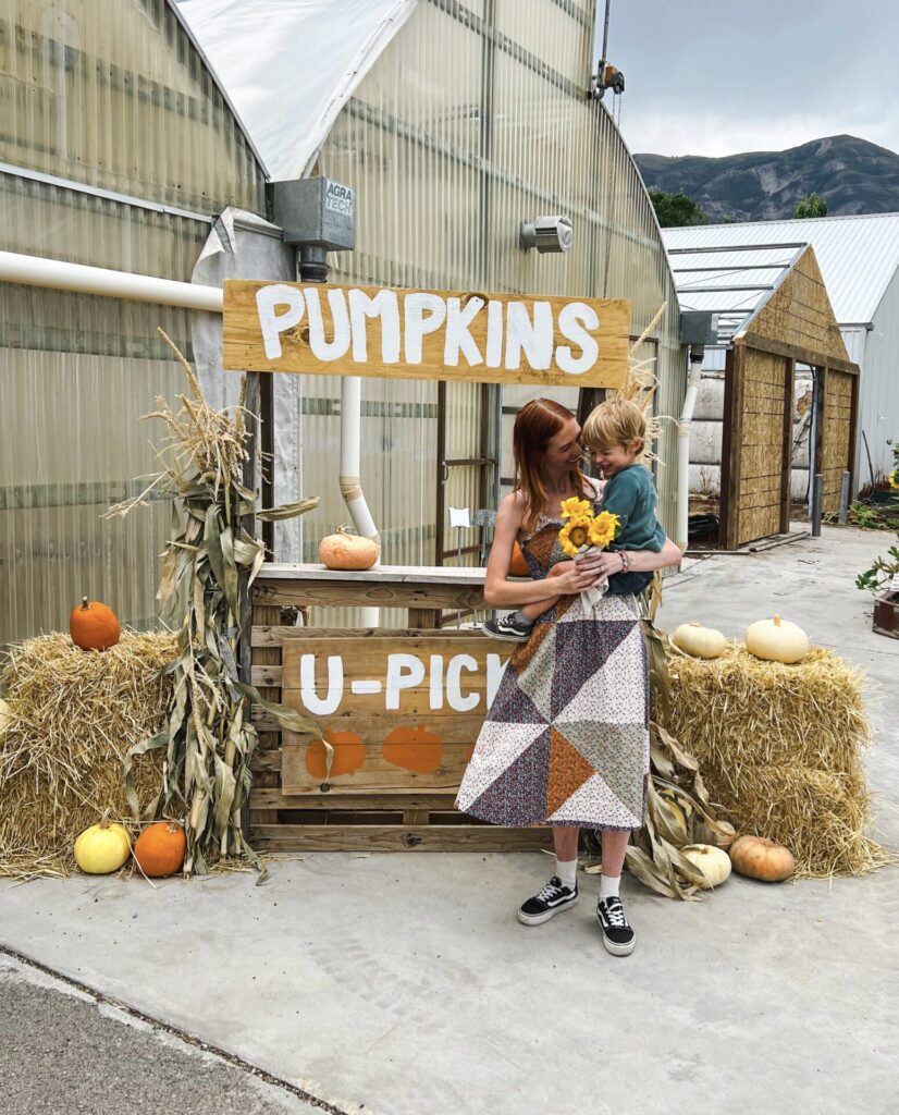 mom and toddler in front of pumpkin patch sign in Utah